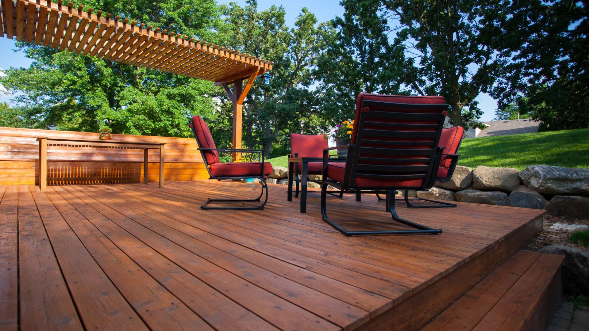 A wooden deck with chairs and a pergolated area
