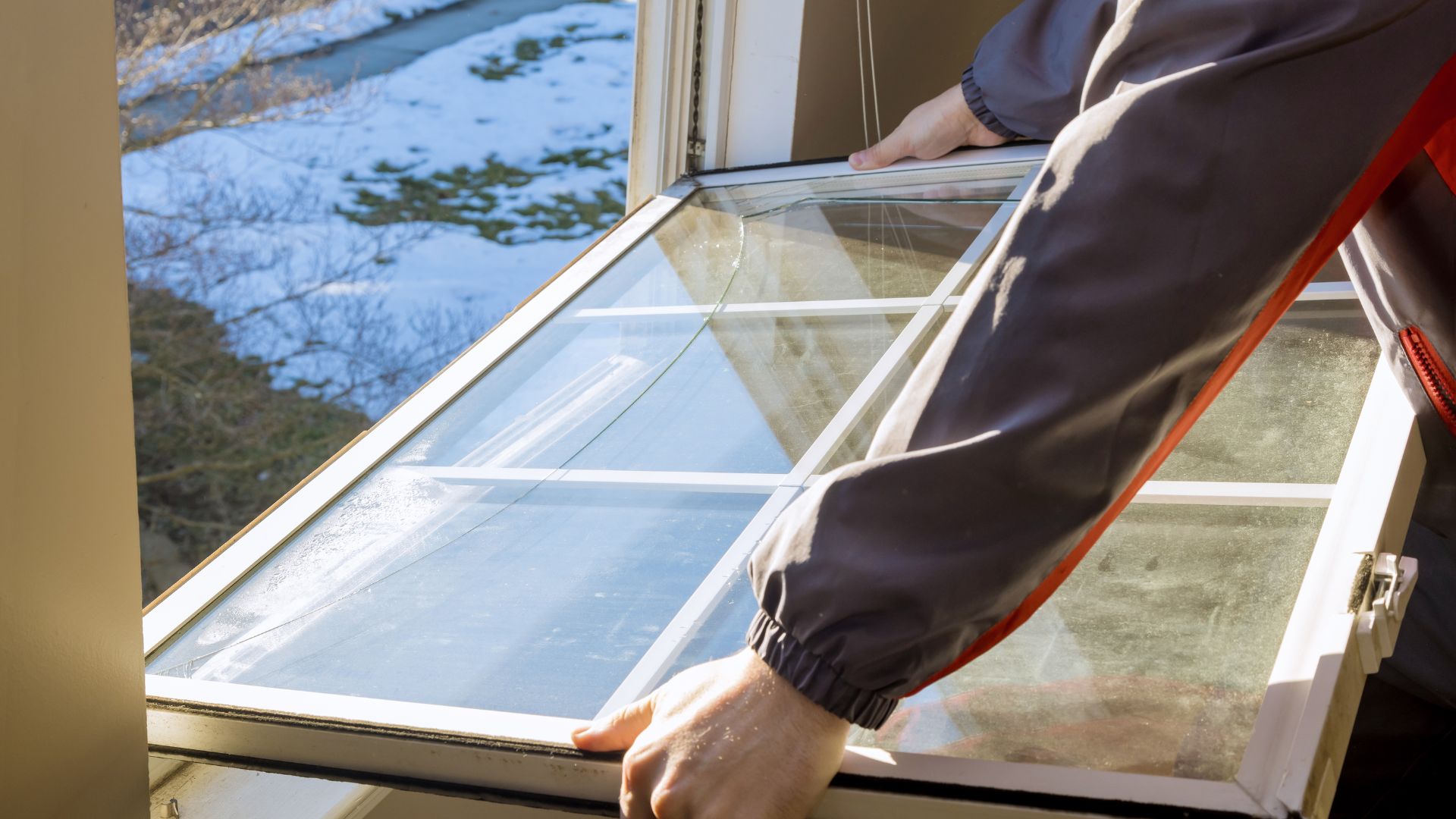 A person is holding a window open to see the snow outside