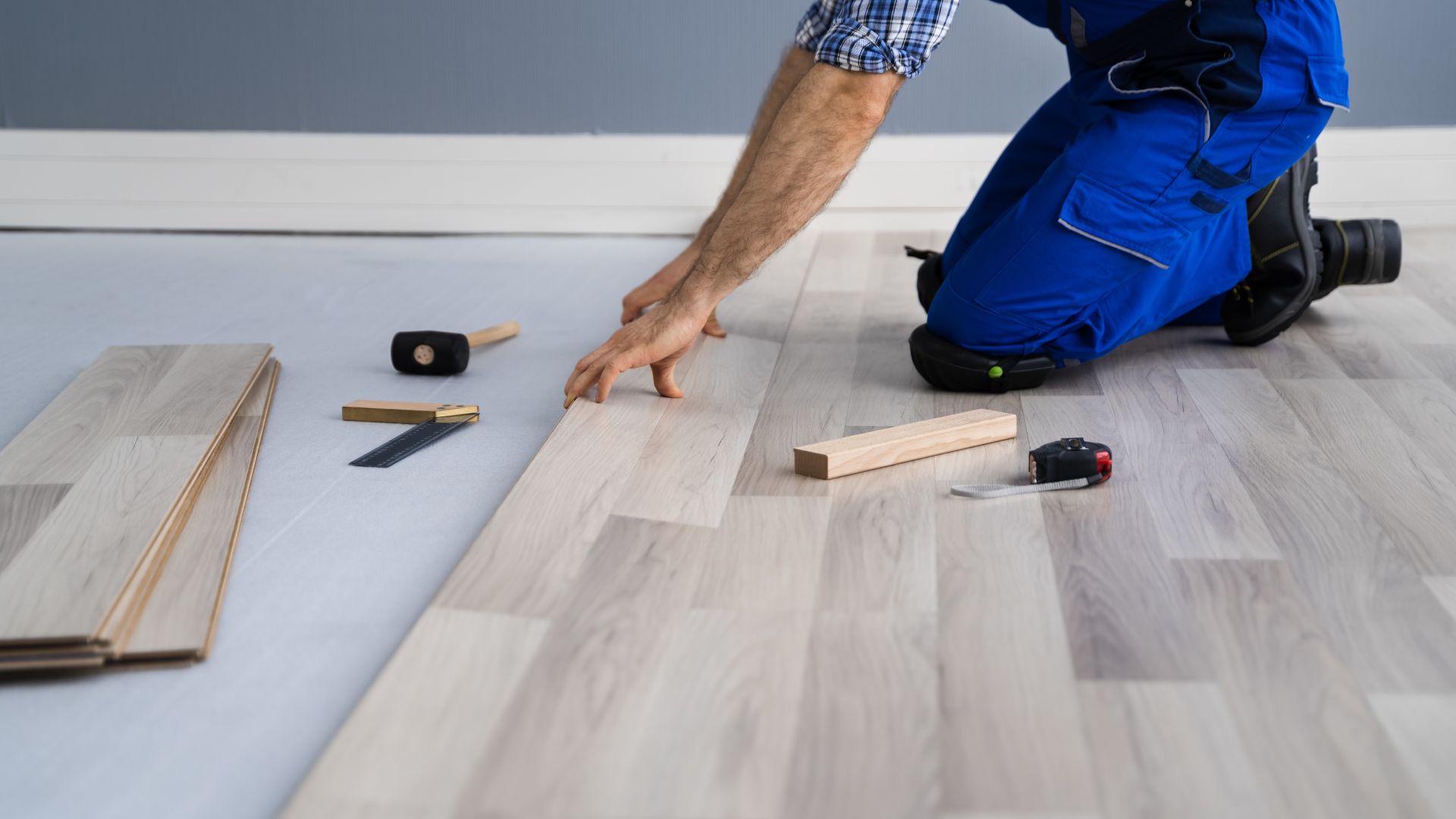 A man working on a hardwood floor with tools