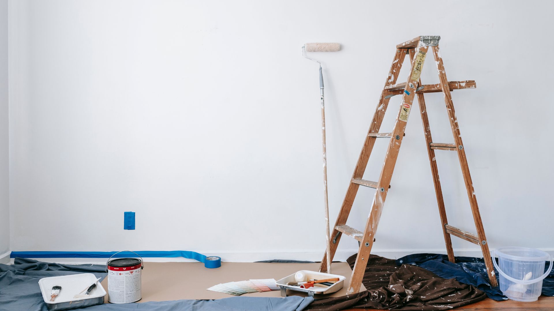 A room with a ladder and a bucket of paint